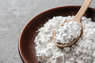 Powdered white sugar with stevia pills in bowl on grey table, closeup