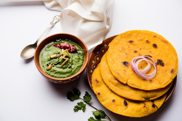 Makki di roti with sarson ka saag, popular punjabi main course recipe in winters made using corn breads mustard leaves curry. served over moody background. selective focus