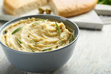 Bowl with tasty hummus on light table