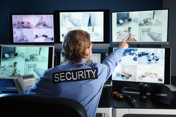 Security guard monitoring modern CCTV cameras in surveillance room