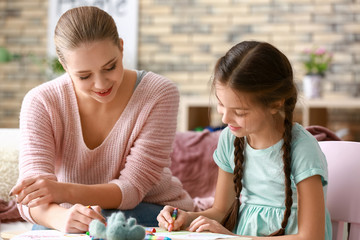 Cute girl with mother doing homework at home