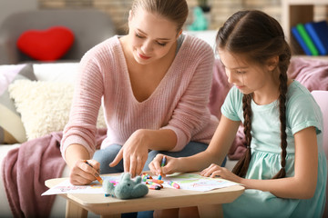 Cute girl with mother doing homework at home