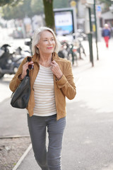 Fototapeta premium Attractive senior woman walking through town