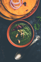 Makki di roti with sarson ka saag, popular punjabi main course recipe in winters made using corn breads mustard leaves curry. served over moody background. selective focus
