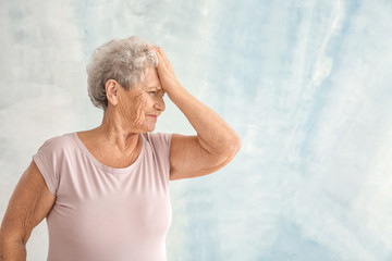 Portrait of elderly woman after making mistake on light background
