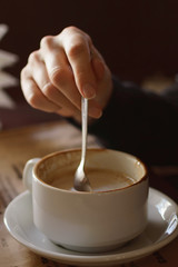 The girl stirs sugar in a cup of coffee. Close-up, lifestyle.