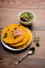 Makki di roti with sarson ka saag, popular punjabi main course recipe in winters made using corn breads mustard leaves curry. served over moody background. selective focus