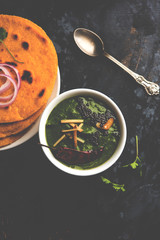 Makki di roti with sarson ka saag, popular punjabi main course recipe in winters made using corn breads mustard leaves curry. served over moody background. selective focus