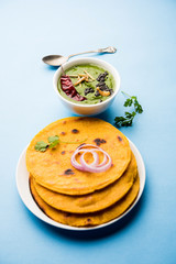 Makki di roti with sarson ka saag, popular punjabi main course recipe in winters made using corn breads mustard leaves curry. served over moody background. selective focus