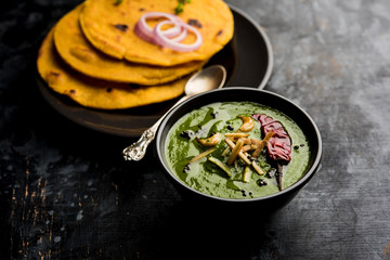 Makki di roti with sarson ka saag, popular punjabi main course recipe in winters made using corn breads mustard leaves curry. served over moody background. selective focus