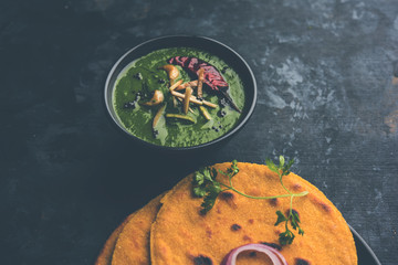 Makki di roti with sarson ka saag, popular punjabi main course recipe in winters made using corn breads mustard leaves curry. served over moody background. selective focus