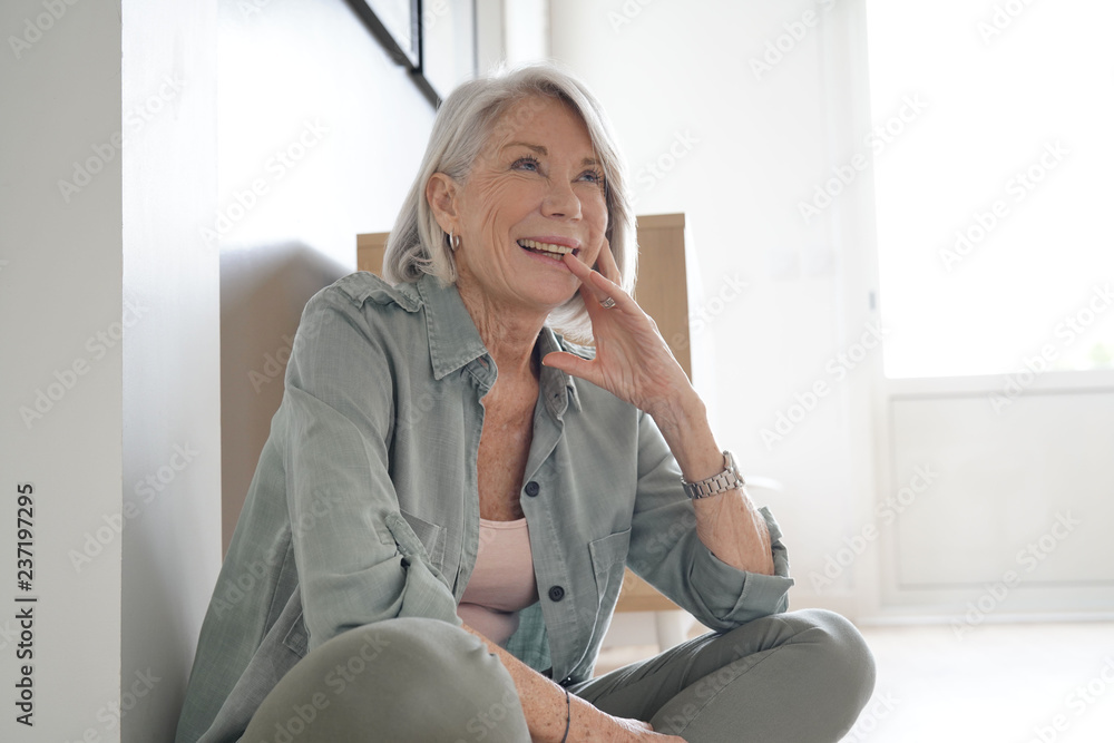 Wall mural  Attractive senior woman sitting on the floor at home