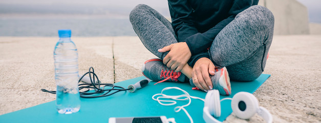 Low section of woman sitting on yoga mat with sport accessories