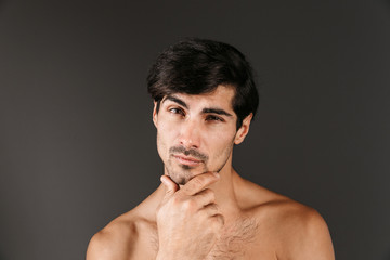 Fototapeta premium Handsome thoughtful serious young smiling man posing isolated over dark wall background.