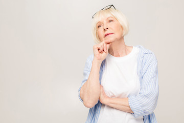 Portrait of thinking senior woman isolated over white background.