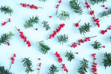 Christmas modern composition. Pattern made of green fir tree branches and red berries on pastel blue background. Christmas, New Year, winter concept. Flat lay, top view, copy space