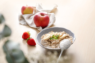 Plate with tasty oatmeal and banana slices on wooden table