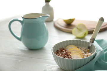 Bowl with tasty oatmeal, sliced pear and sesame seeds on white table