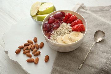 Bowl with tasty oatmeal, fruits and strawberry on white table
