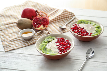 Plates with tasty oatmeal and fruits on white wooden table