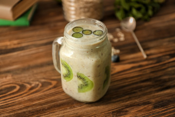 Mason jar with tasty oatmeal and fruits on wooden table