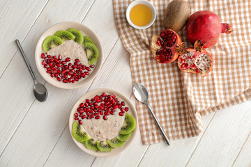Plates with tasty oatmeal and fruits on white wooden table