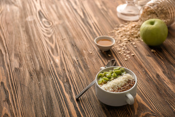 Casserole with tasty oatmeal, sesame seeds and kiwi on wooden table
