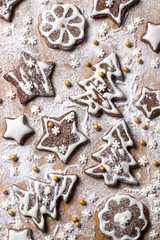 Christmas homemade chocolate cookies decorated with icing and powdered sugar on a wooden background, top view