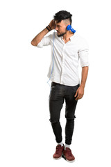 Fototapeta premium A full-length shot of a Arabic young man with white shirt listening to music with headphones on isolated white background