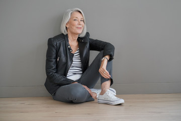  Modern senior woman sitting indoors with leather jacket