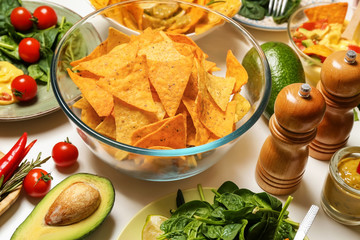 Glass bowl with tasty corn chips on white table