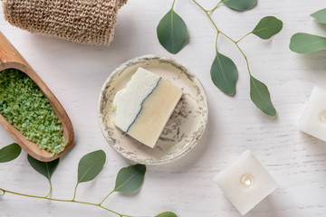 Composition with burning candles, eucalyptus branches, sea salt and soap bar on white background