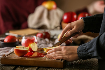 Obraz na płótnie Canvas Woman cutting fresh apple at wooden table