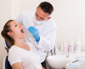 Obraz na płótnie Canvas Dentist is treating woman patient which is sitting in dental chair