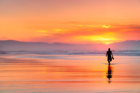 lonely person walking on beach at beautiful red sunset - Powered by Adobe