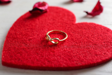 Red heart with engagement ring on table, closeup