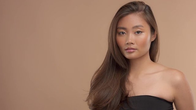panned video portrait of thai asian model in studio with ideal strobing skin and straighr hair. Slow motio from 60fps