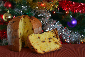 panettone tagliato, una fetta pronta da mangiare, sullo sfondo addobbi di natale