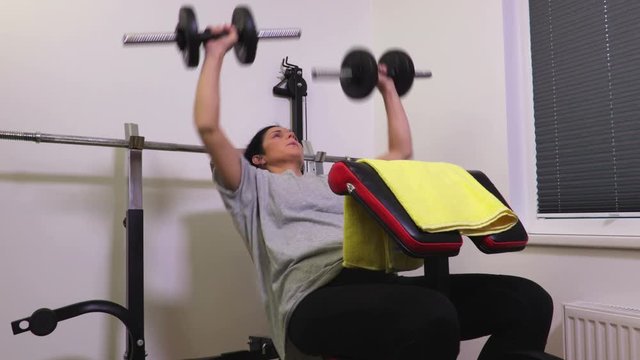 Woman on gym bench doing exercises for chest