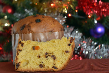 panettone tagliato, una fetta pronta da mangiare, sullo sfondo addobbi di natale
