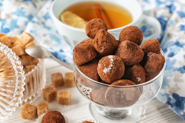 Glass bowl with tasty chocolate truffles on table, closeup