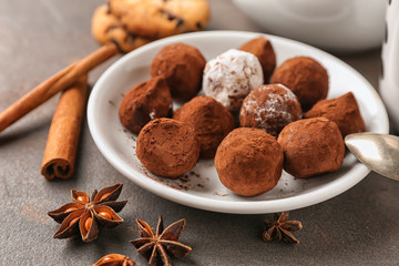Plate with tasty chocolate truffles on grey table