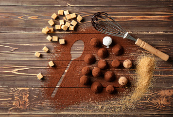 Tasty chocolate truffles powdered with cacao on wooden table