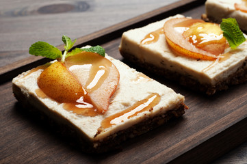 Dessert. Paste from coconut milk, cashew nuts and sugar-free syrup on a cushion of seeds, dried fruits and nuts. On the top are pear slices and syrup. No baking. Macro shooting, selective sharpness