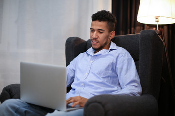 Young African-American man working with laptop at home