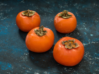 Ripe orange fig persimmon fruit on a blue grunge background. Flat lay. Top view. Copy space