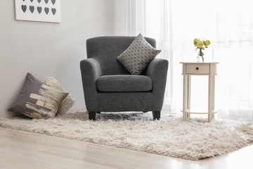 Interior of light room with cozy armchair near window