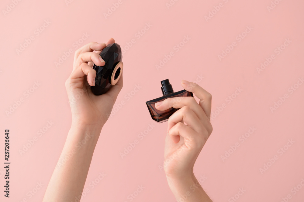 Wall mural woman holding bottle of perfume on color background