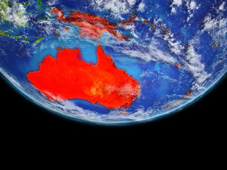 Australia from space on model of planet Earth. Extremely fine detail of planet surface and clouds. Continent highlighted in red.