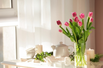 Vase with beautiful tulips on glass table